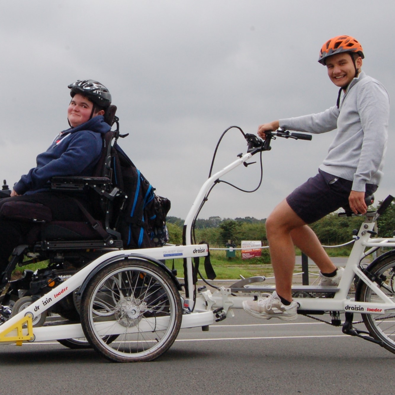 A carer and young wheelchair user on an adapted bike.