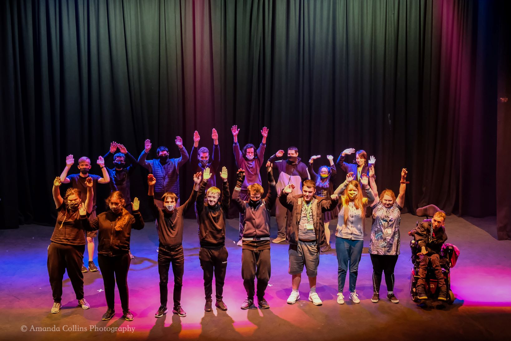 A group of young adults standing on the stage at the Trinity Theatre.