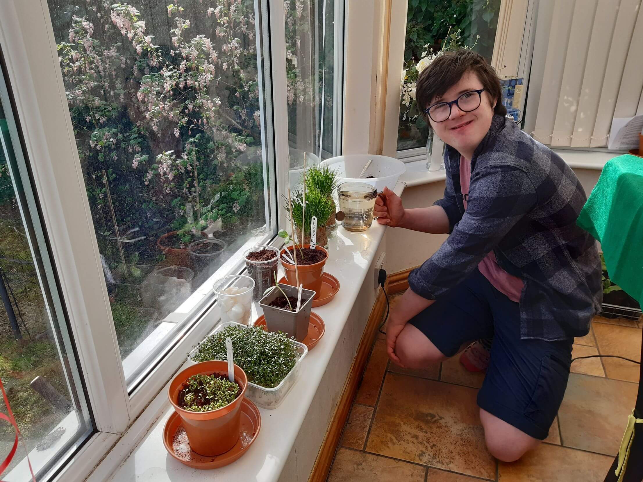 A teenage boy watering plants he has grown.