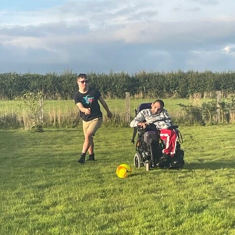 Two men playing football. One man is a wheelchair user.