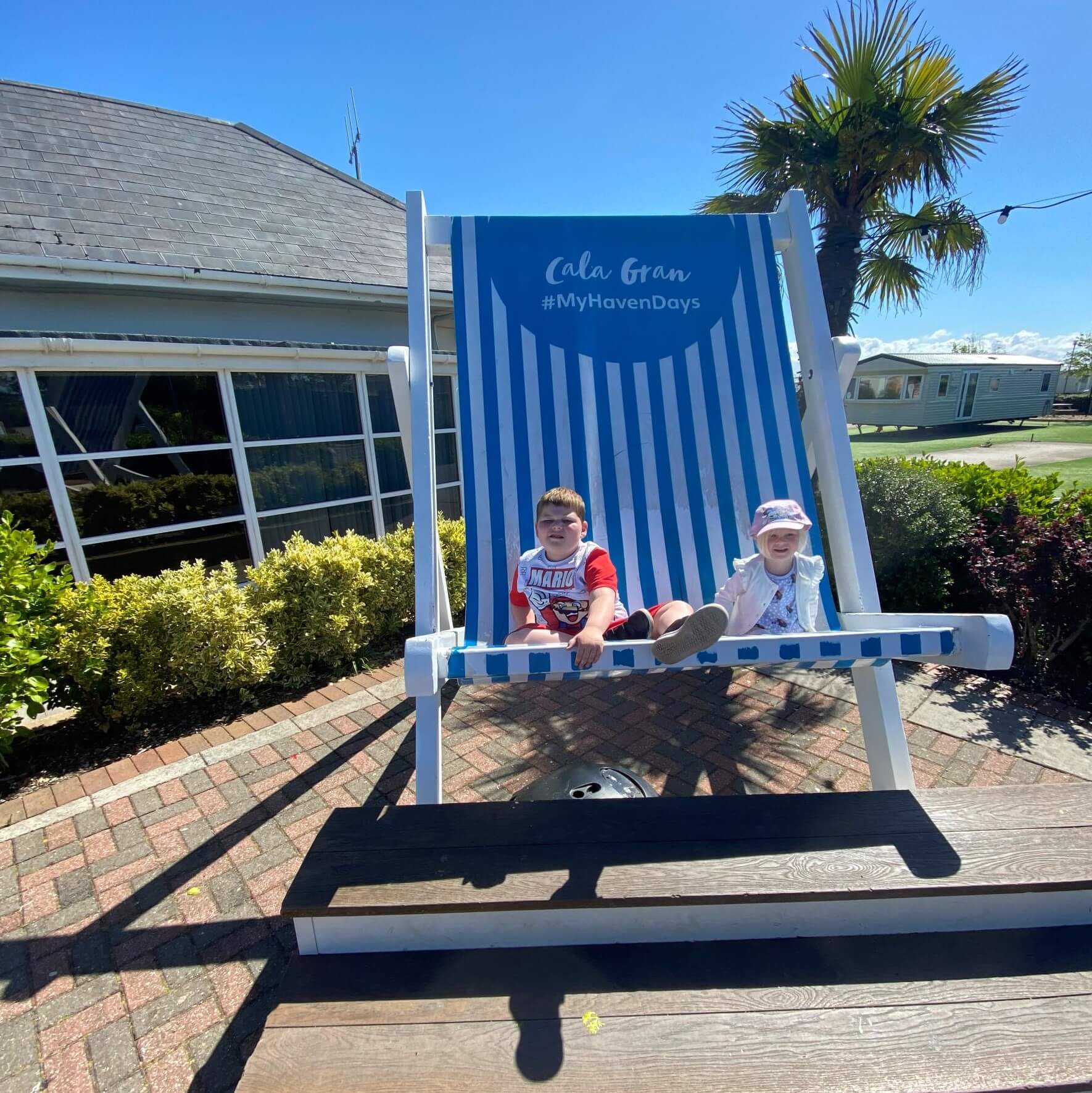 Two young children in a large deckchair whilst on holiday.