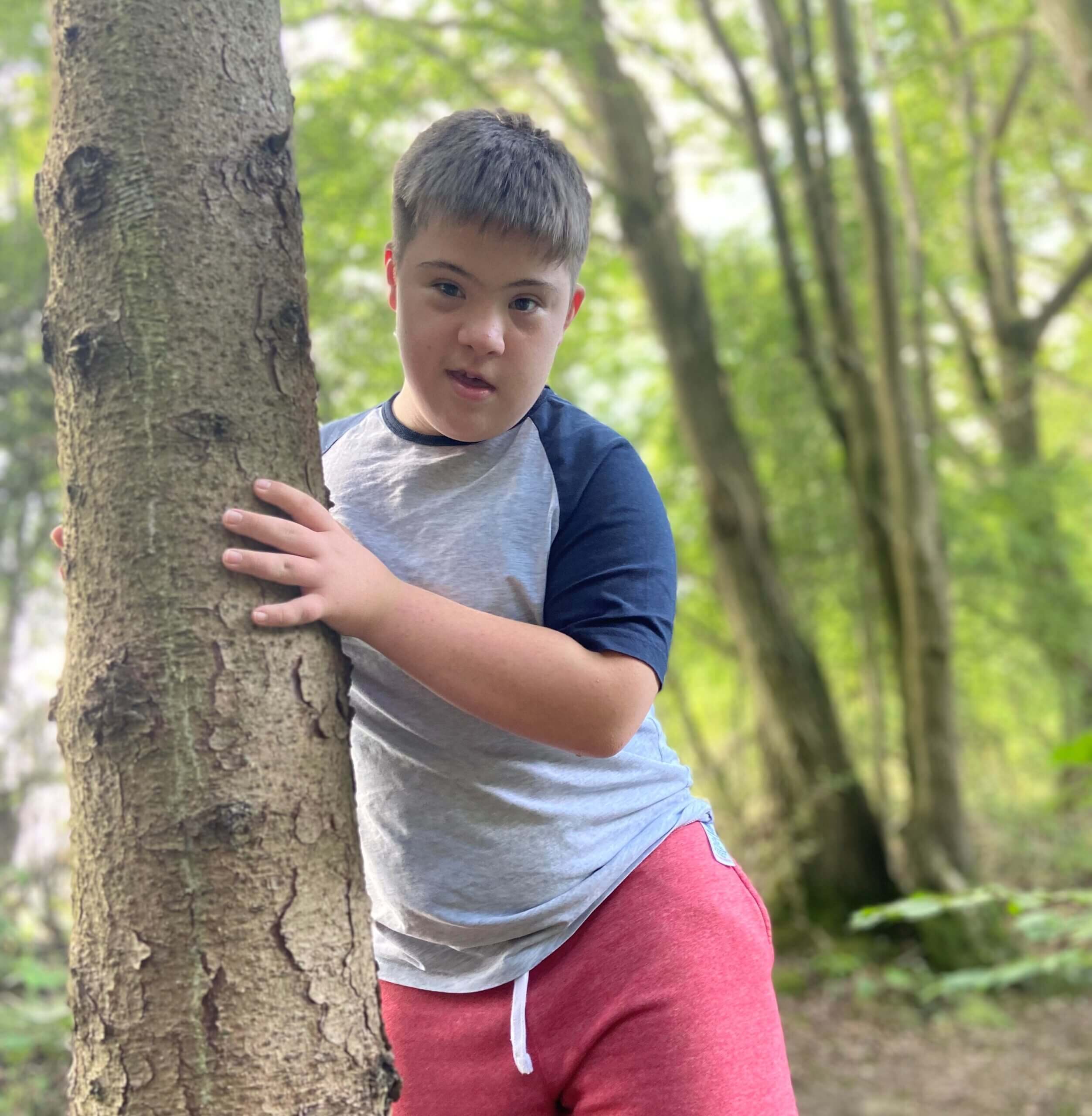 A young boy standing by a tree while on a holiday funded by a holiday grant.
