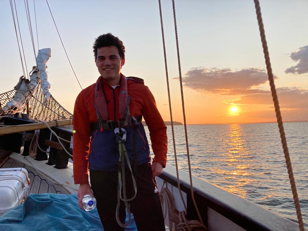 A young carer standing on the boat at sunset.