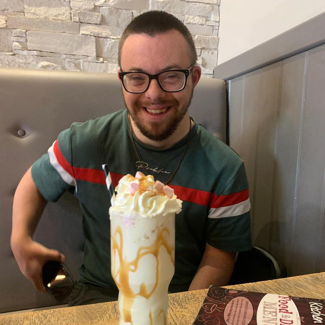 A guest just about to enjoy a large milkshake topped with cream and marshmallows.
