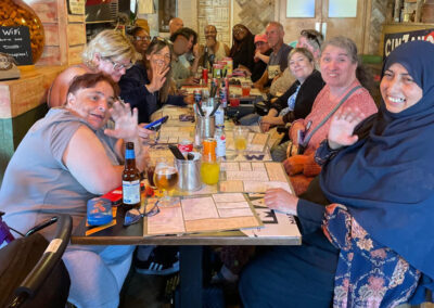 A group of men and women sitting around a large tale enjoying a meal out at an Italian restaurant.
